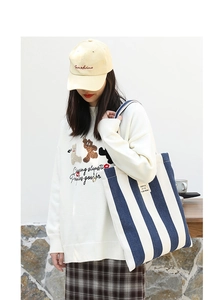 Close-up of a striped canvas tote bag with letter print and casual lifestyle outfit