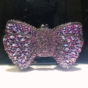 Macro detail of bow-shaped clutch encrusted with purple and pink sparkling rhinestones