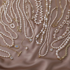 Vintage freshwater pearl necklaces with heart and geometric pendants on silk background