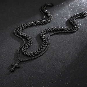 Close-up of black double-layered stainless steel necklace with cross pendant and curb chain