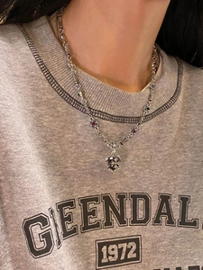 Close-up of a vintage punk heart cross necklace with red and green gemstone accents