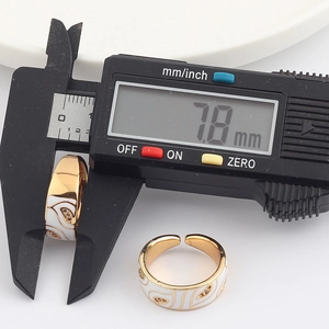 Digital caliper measuring the 7.8mm width of a gold-plated enamel ring with zircons