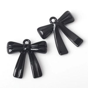 Detail of two glossy black alloy bow charms with small rings for DIY jewelry making