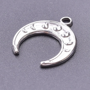 Macro shot of silver crescent moon pendant with engraved star details on steel