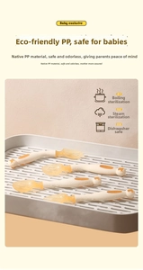 Baby fork and spoon set in orange and white on a drying rack for infant feeding
