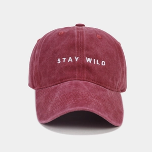 Dettaglio macro del ricamo 'STAY WILD' sul cappello bordeaux in cotone lavato