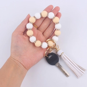 Silicone bead wristlet keychain with white and beige beads, gold rhinestones, and white tassel