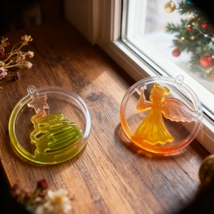 Christmas tree and angel liquid pendants in clear frames on a rustic wooden windowsill