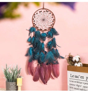 Detail of bohemian dream catcher with peacock blue feathers and white beaded mesh