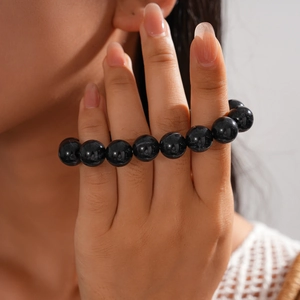 Close-up of black acrylic beaded necklace featuring smooth polished round stones