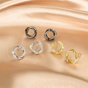 Macro view of intertwined double-loop earrings in black, silver and gold with zircons