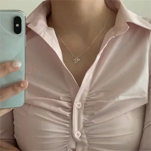 Mirror selfie showing a silver bow pendant necklace worn with a pink shirt outfit