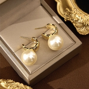 Elegant diamond-pattern gold pearl earrings displayed in a luxury grey silk jewelry box