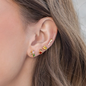 Detailed view of gold mermaid stud earring set with cubic zirconia on a model's ear