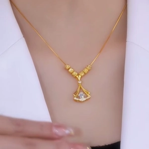 Close-up of a gold fan-shaped necklace with zircon pendant worn on neck with white suit