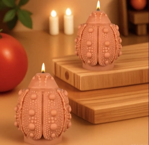 Detail of red beetle shaped candles with textured surface and burning cotton wicks