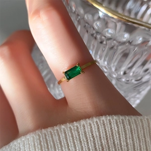 Macro shot of 18K gold plated ring featuring a rectangle emerald stone on a finger