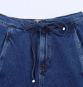 Dettaglio della vita in denim blu scuro con coulisse regolabile e punte in metallo