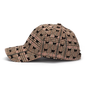 Detail of British plaid baseball cap featuring small black bow patterns and fine stitching