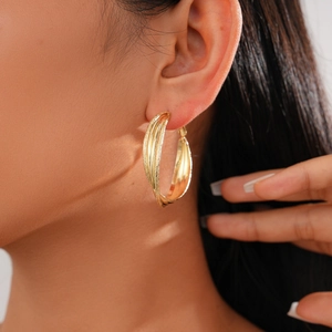 Detail of 18k gold plated geometric layered hoop earrings shown on a model