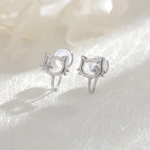 Macro view of silver cat-shaped ear clips with sparkling white zircon and soft silicone pads