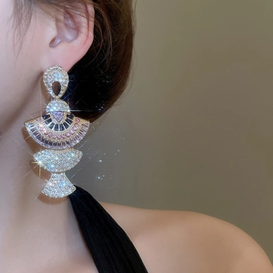 Close-up of luxury gold fan-shaped earrings with pink crystals and shimmering stones