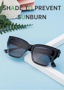 Macro shot of cat eye sunglasses with grey gradient frames on a blue stone background