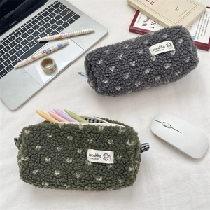 Trousses en peluche gris et vert olive présentées sur un bureau avec un décor de travail