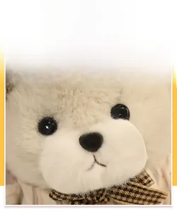 Dettaglio di un coniglietto di peluche color crema con pelliccia riccia e fiocco a quadri