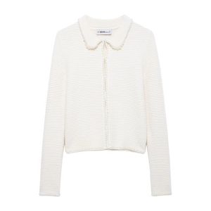 Gros plan d'un gilet blanc en maille avec détails en perles et étiquette de marque