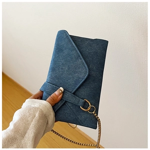 Detail of blue denim envelope bag with golden ring buckle and chain strap