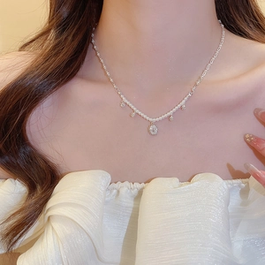 Detail of silver pearl necklace with floral pavé pendant on model's neckline