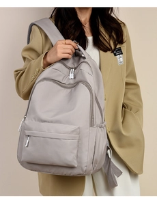 Minimalist grey nylon backpack shown on model in a professional office suit style
