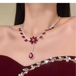 Detail of elegant silver necklace with red pear-cut zircon stones on a model