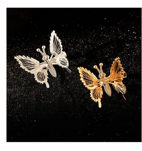 Detail of hollow metal butterfly hair clips with gold and silver mesh wings on dark background