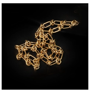 Detailed close-up of 18K gold knot link chain necklace on black leather texture background