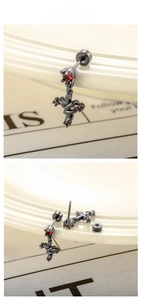 Macro shot of gothic snake cross earring with red zircon inlay and black metal finish