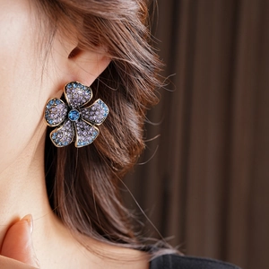 Gros plan sur boucle d'oreille fleur vintage avec cristaux violets et bleus sur modèle
