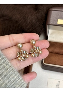 Close-up of elegant flower earrings with gold pearls and champagne crystals held by hand