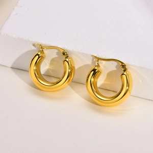 Detailed view of chunky 18K gold-plated hollow hoop earrings on a white stone base