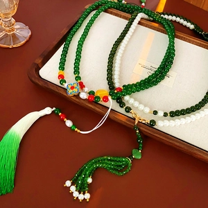 Détail de colliers en perles avec de longs glands et pendentifs en émail sur un plateau