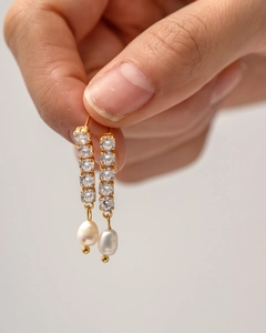 Detail of long tassel earrings with micro-set zircons and white drop pearls in gold finish