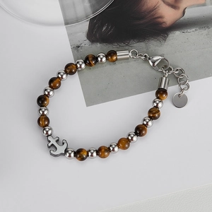 Detail of beaded bracelet featuring tiger eye stones and silver anchor charm with clasp