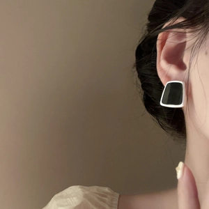 Detailed view of geometric black resin stud earrings with silver metal frame on model