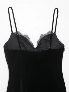 Detailed view of black velvet dress with delicate lace trim and thin straps on white background
