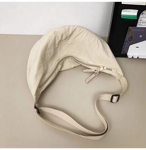 Détail du sac croissant en nylon beige avec bandoulière réglable et ferrures lisses