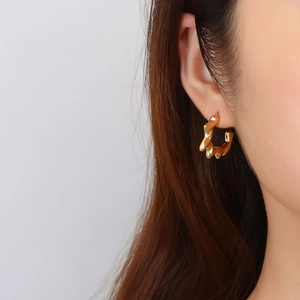 Irregular lava-shaped 18K gold plated stainless steel earrings shown on a model
