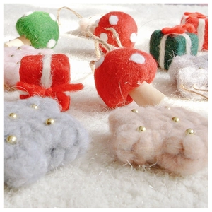 Close-up of wool felt Christmas tree decorations featuring mushrooms and stars