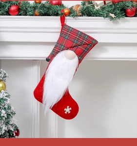 Detail of red plaid Christmas stocking with gnome figurine hanging on festive fireplace