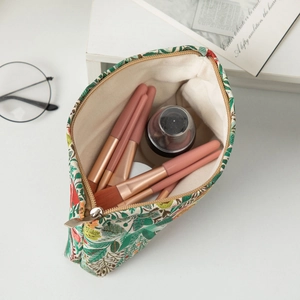 Macro detail of floral embroidery makeup bag showing green jacquard fabric and metal zipper